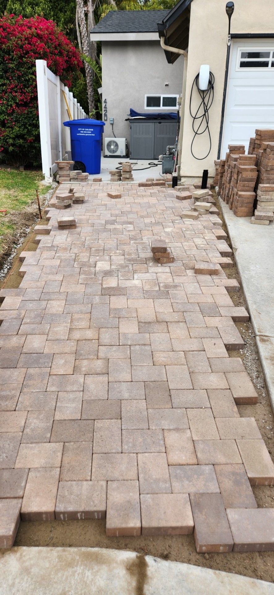 Paver driveway during installation with pallets of stock alongside