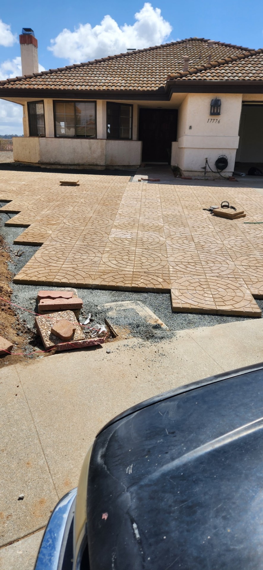 Tan circle-pattern pavers being installed in front of a tile-roof home