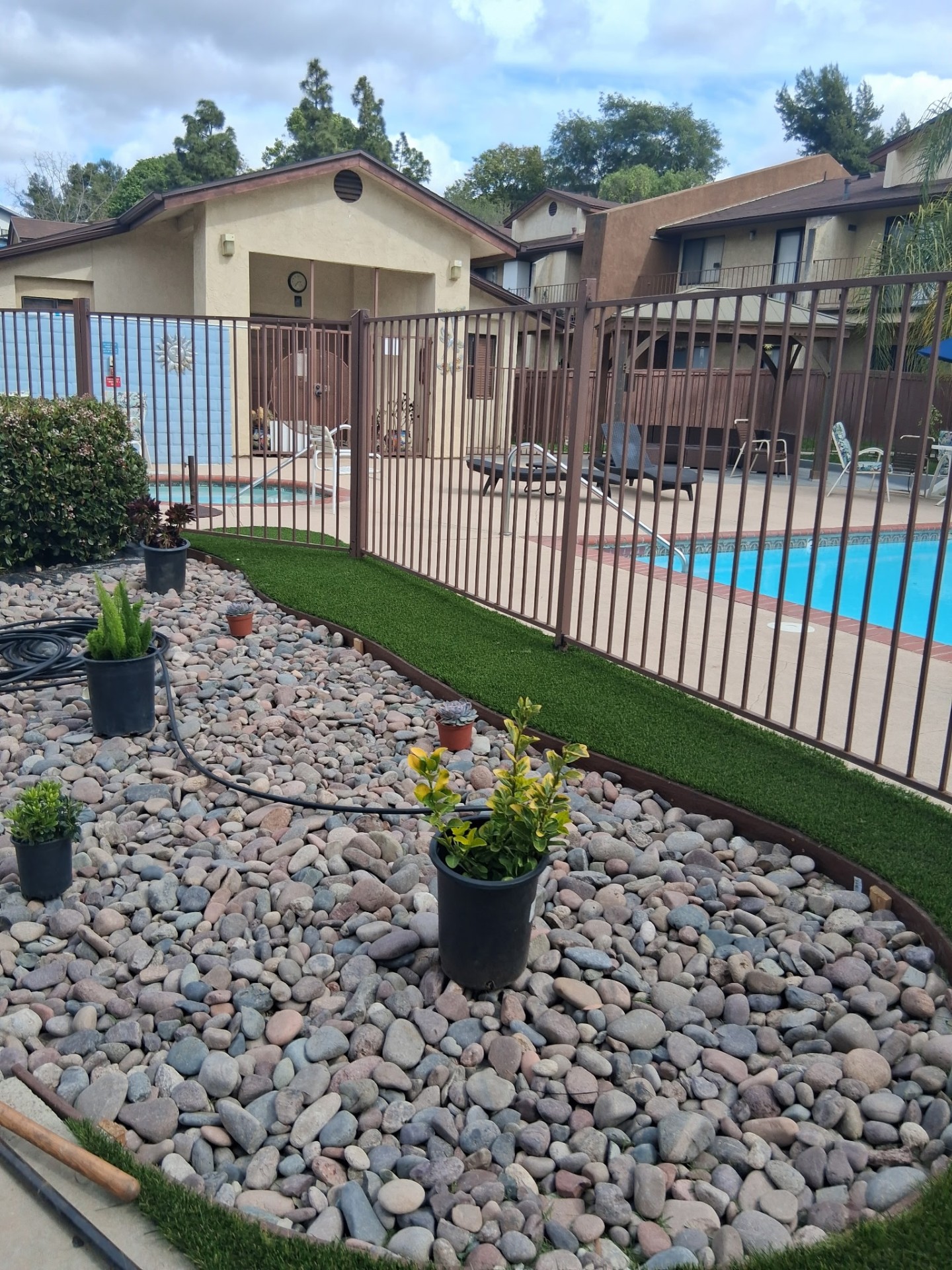River rock landscaping and artificial turf around a pool area