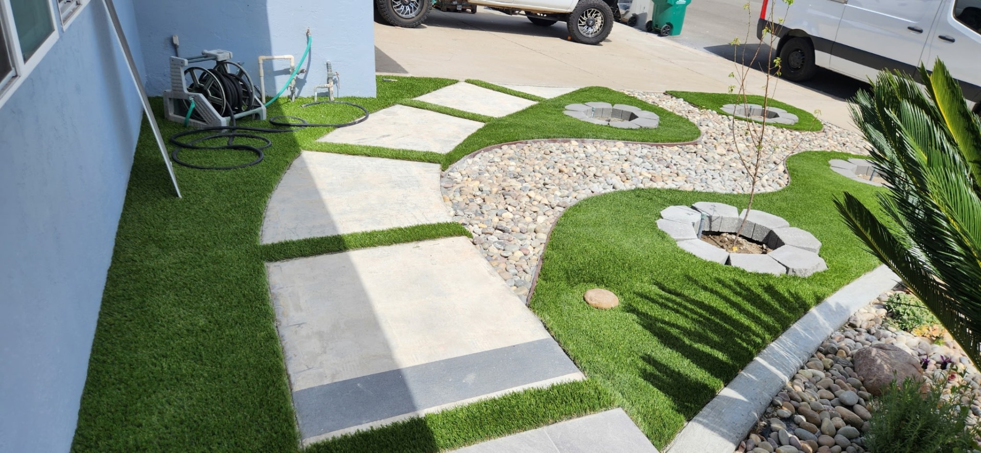 Front yard with artificial turf, flagstone stepping stones, river rock bed and circular planter rings